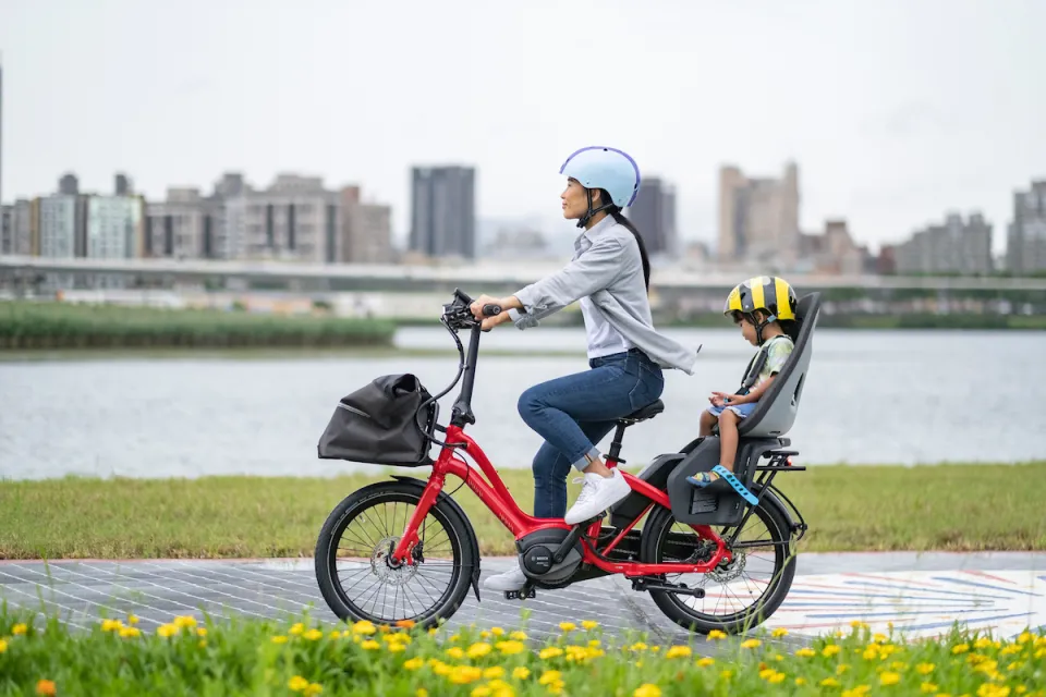 Woman riding Tern NBD e-bike while carrying a child in a child seat