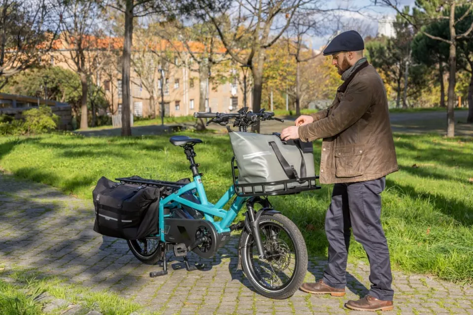 Man loading a front cargo bag on a Tern GSD electric cargo bike equipped with rear panniers.